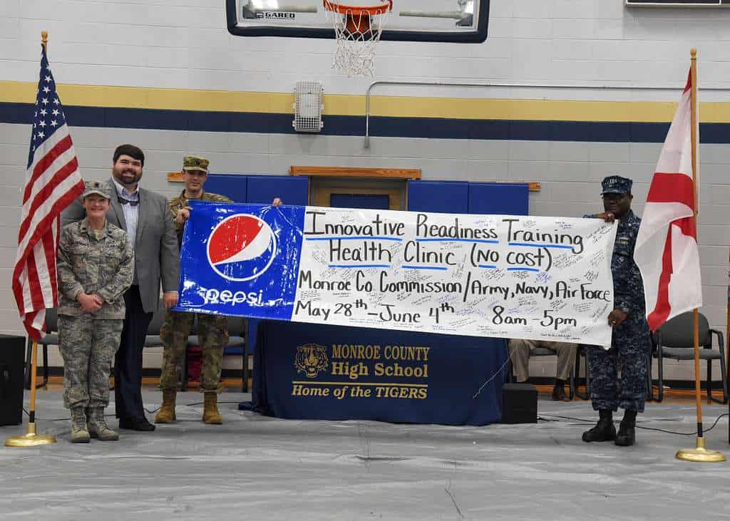 Military personnel and community members promote a no-cost health clinic at Monroe County High School.